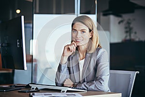 Happy and successful business woman boss working at computer in modern office looking at camera and smiling