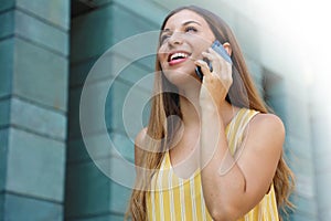 Happy successful business woman walking in the street and talking with mobile phone