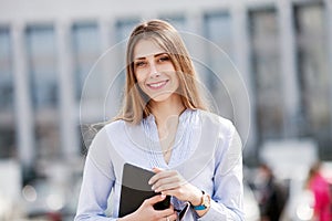 Happy successful businesswoman in blue shirt holding touch pad and smiling
