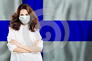 Happy successful doctor or nurse in medical face mask on Finnish flag background. Flu epidemic and virus protection in Finland