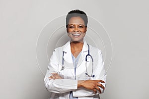 Happy successful doctor woman medical worker in white lab coat standing with crossed arms on white background