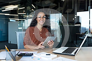 Happy and successful hispanic woman working inside modern office building, business woman using tablet computer smiling