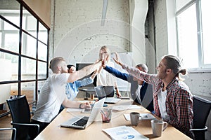 Happy successful multiracial business team giving a high fives gesture as they laugh and cheer their success.