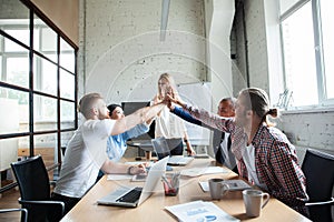 Happy successful multiracial business team giving a high fives gesture as they laugh and cheer their success.