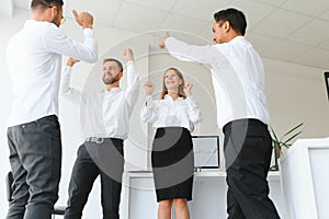 Happy successful multiracial business team giving a high fives gesture as they laugh and cheer their success.
