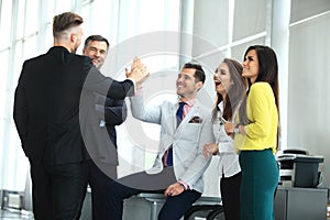 Happy successful multiracial business team giving a high fives gesture as they laugh and cheer their success