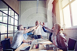 Happy successful multiracial business team giving a high fives gesture as they laugh and cheer their success.