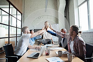 Happy successful multiracial business team giving a high fives gesture as they laugh and cheer their success.