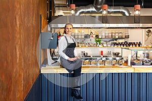 Happy successful new restaurant owner sitting on counter proud of her small business