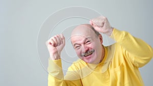 Happy successful pensioner or business man winning, fists pumped celebrating success isolated grey wall background.