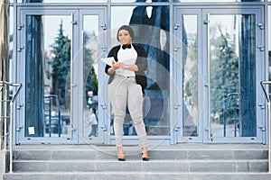 Happy successful professional posing near office building. Young African American business woman standing outside. Female business