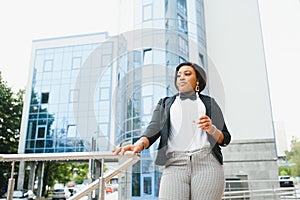 Happy successful professional posing near office building. Young African American business woman standing outside. Female business