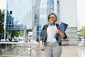 Happy successful professional posing near office building. Young African American business woman standing outside. Female business