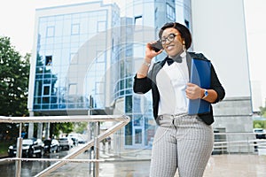 Happy successful professional posing near office building. Young African American business woman standing outside. Female business