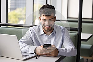 Happy successful young Arab freelance worker using digital gadgets