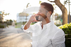 Happy successful young businessman in formal wear having phone conversation while walking outdoors buring break