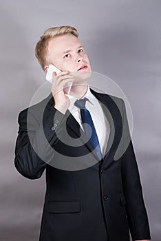 Happy successful young businessman standing talking on cell phone, mobile