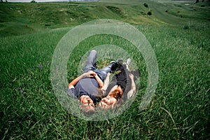 Happy summer couple on vacation. Lovers lie on the grass. Happy guy and girl. Beautiful girl with long dark hair and a young guy.
