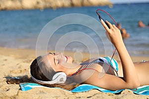 Happy sunbather listening to music with smart phone photo