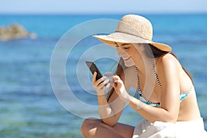 Happy sunbather using smart phone on the beach photo