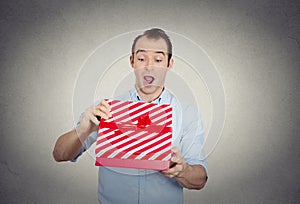 Happy super excited surprised young man about to open unwrap red gift box