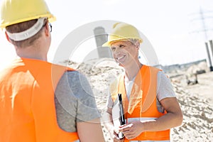 Happy supervisor discussing with colleague at construction site