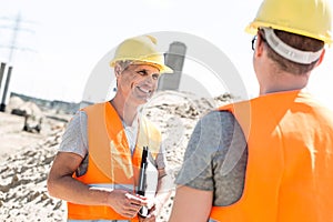 Happy supervisor discussing with colleague at construction site