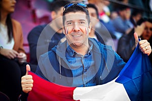 Happy supporter holding french national flag in hands at football match
