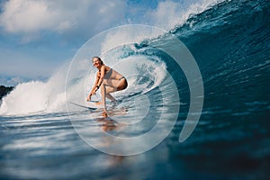 Happy surfer girl at surfboard ride on ocean wave. Woman in ocean during surfing.