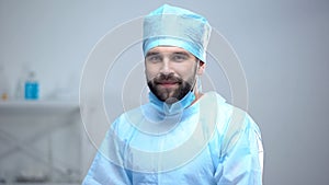 Happy surgeon in medical face mask smiling after successful operation, work