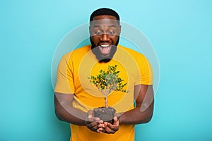 Happy surprised boy hold a small tree ready to be planted. Concept of forestation