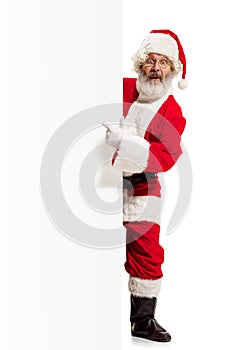 Happy Santa Claus pointing on blank advertisement banner background with copy space. Smiling Santa Claus pointing in