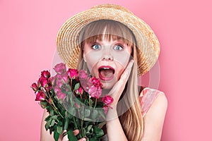 Happy surprised woman in straw hat holding roses on pink background