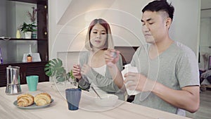 Happy sweet Asian couple having breakfast, cereal in milk, bread and drinking orange juice after wake up in the morning.