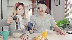 Happy sweet Asian couple having breakfast, cereal in milk, bread and drinking orange juice after wake up in the morning.