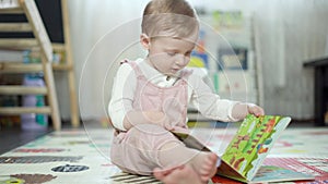 Happy sweet baby girl reading books sitting on the floor