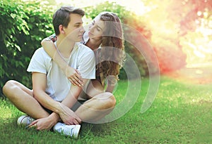 Happy sweet young couple teenagers sitting on the grass in summer