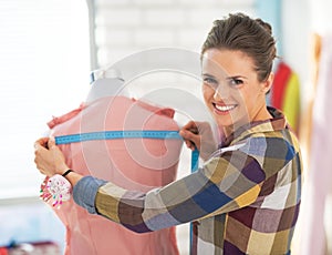 Happy tailor woman working with dress