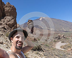 Happy tan Handsome guy with beard holding black hat and joyful, taking a selfie at Teide National Park in Tenerife