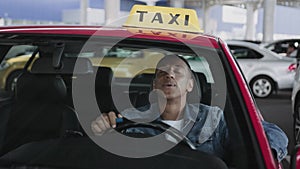 Happy taxi driver smoking an electronic cigarette, sitting in car. Slow motion