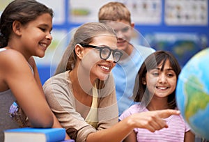 Happy teacher, students and geography with planet or globe of earth in class for education or learning at school. Woman