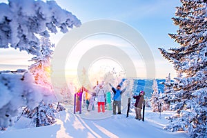 Happy team of snowboarders and skier having fun tossing snow. Light sun in winter forest sunrise