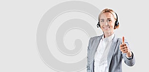 Happy tech support service worker with headset showing thumb up against light studio background, copy space
