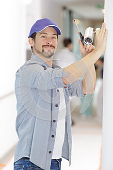 happy technician adjusting cctv camera on wall