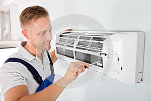 Happy Technician Repairing Air Conditioner photo