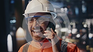 Happy technician speaking mobile phone at industrial production premises closeup