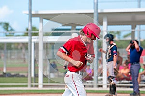 Happy teen baseball player running off field smiling.