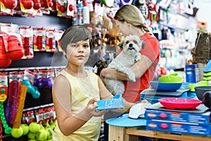 Happy teen boy with mother visiting pet shop in search of accessories for their dog