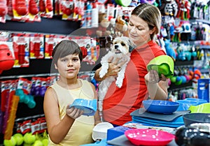 Happy teen boy with mother visiting pet shop in search of accessories for their dog