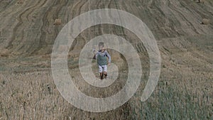 Happy teen boy playing with paper airplane against the background of the harvested field